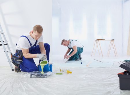 Two young painters are painting the wall in the room